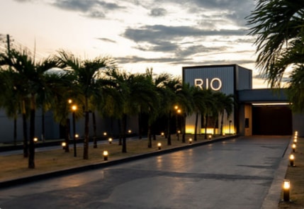 Entrada do Rio Motel ao entardecer, com a alameda de palmeiras iluminada